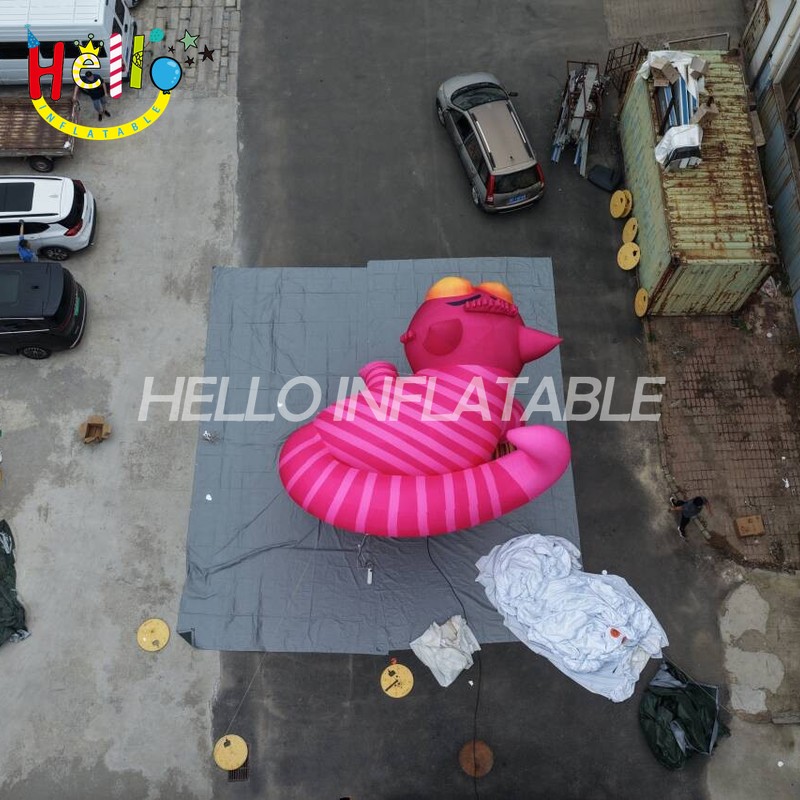 Giant Custom Inflatable Cheshire Cat with Striped Tail, Large Smiling Pink Fantasy Cat Character on Rock Base for Amusement Park and Mall Event Decoration