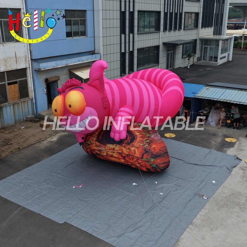 Giant Custom Inflatable Cheshire Cat with Striped Tail, Large Smiling Pink Fantasy Cat Character on Rock Base for Amusement Park and Mall Event Decoration