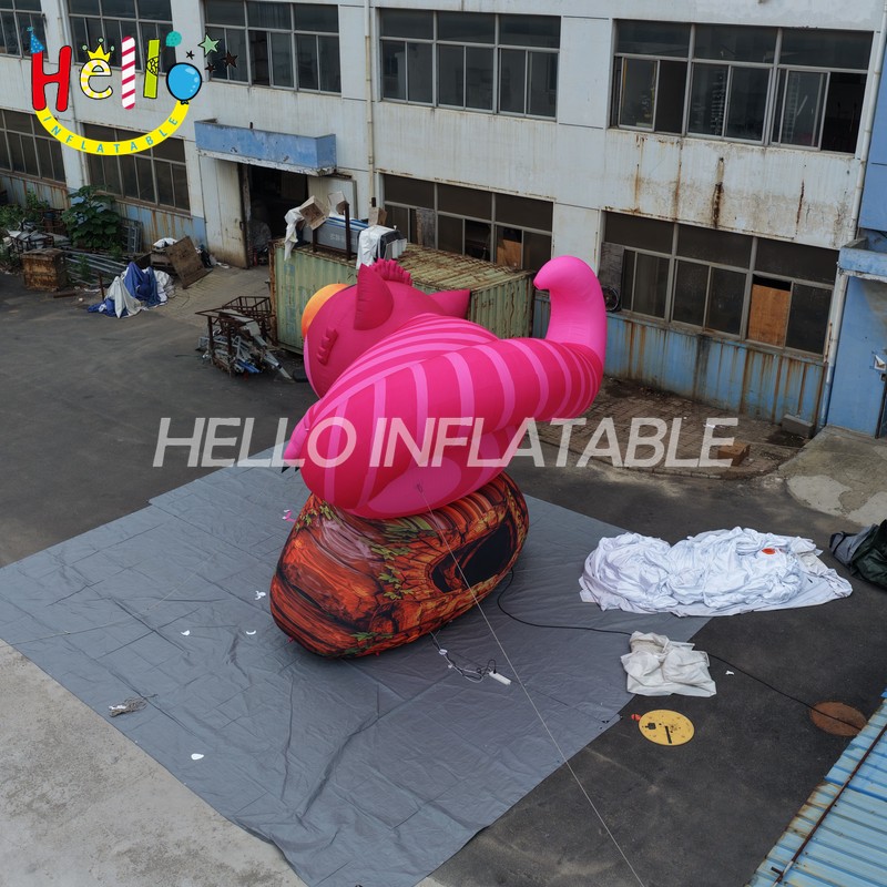 Giant Custom Inflatable Cheshire Cat with Striped Tail, Large Smiling Pink Fantasy Cat Character on Rock Base for Amusement Park and Mall Event Decoration